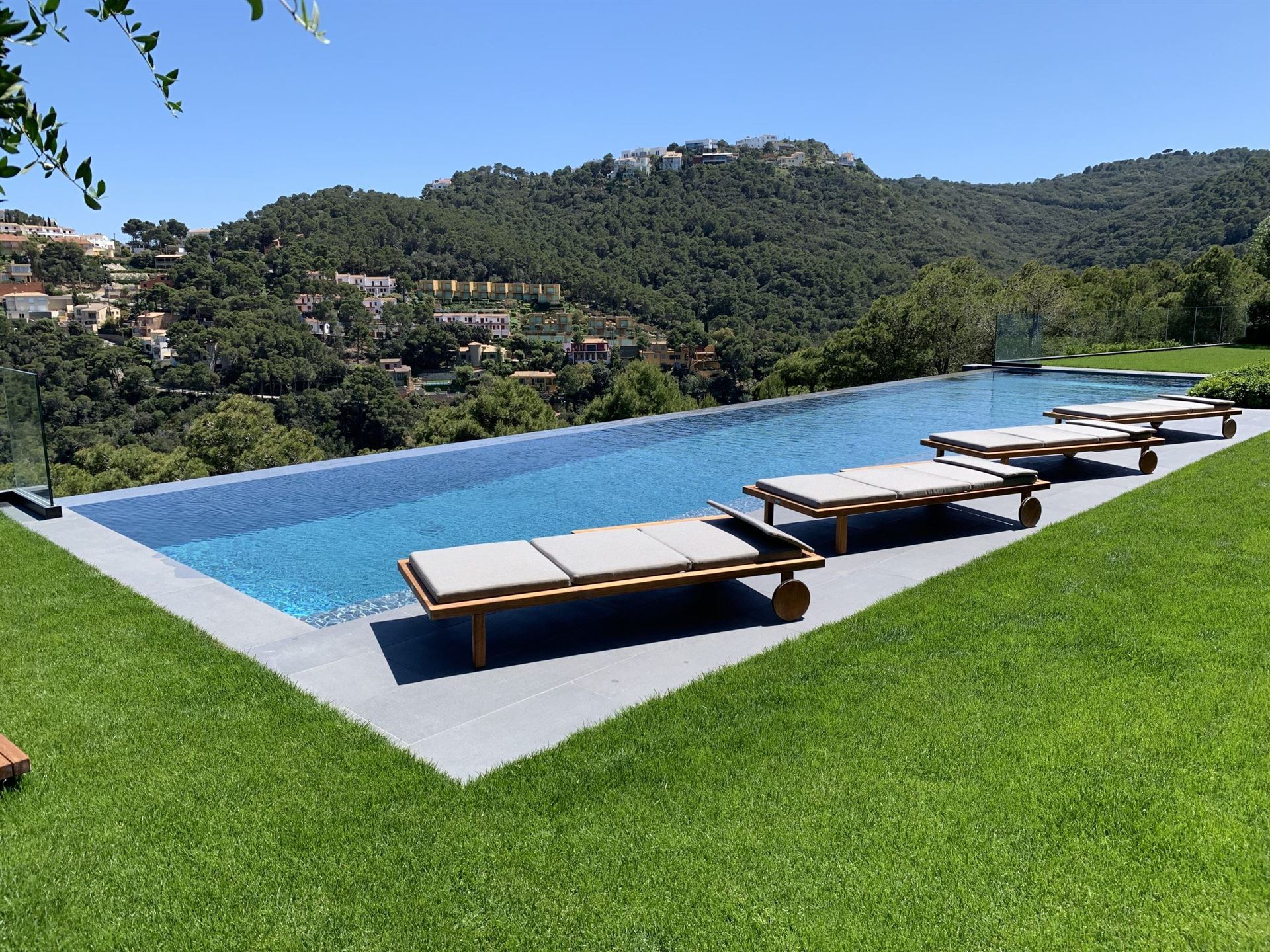 Piscina desbordante con tumbonas y vistas a las montañas